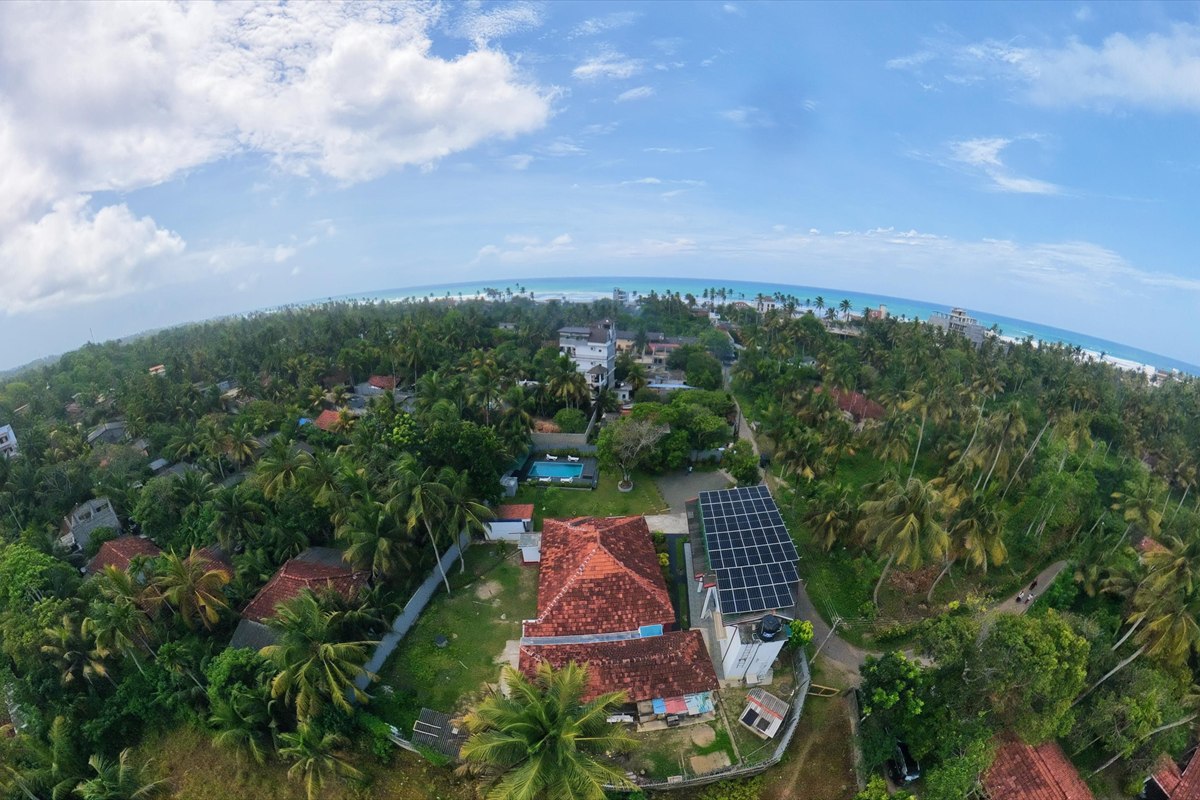 Aerial view of Dimuthu Ahangama among palm trees, with the Indian Ocean beyond