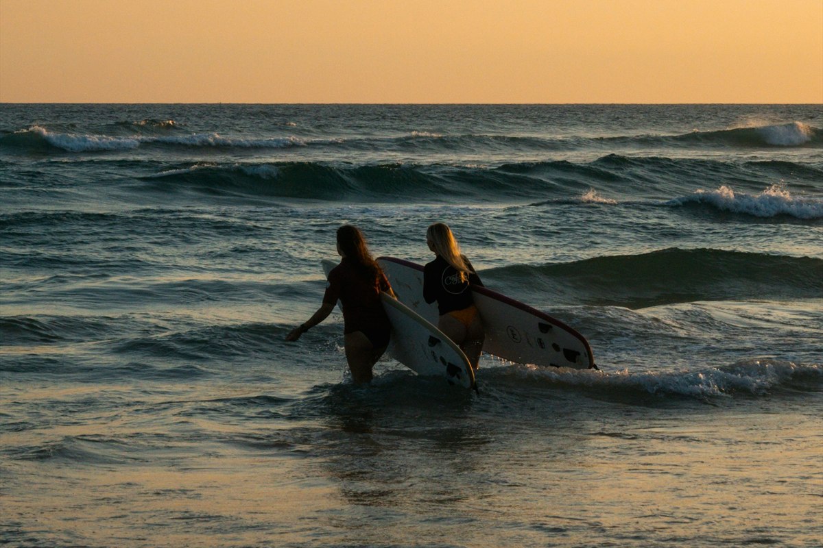 Surfers entering the ocean at sunset in Ahangama