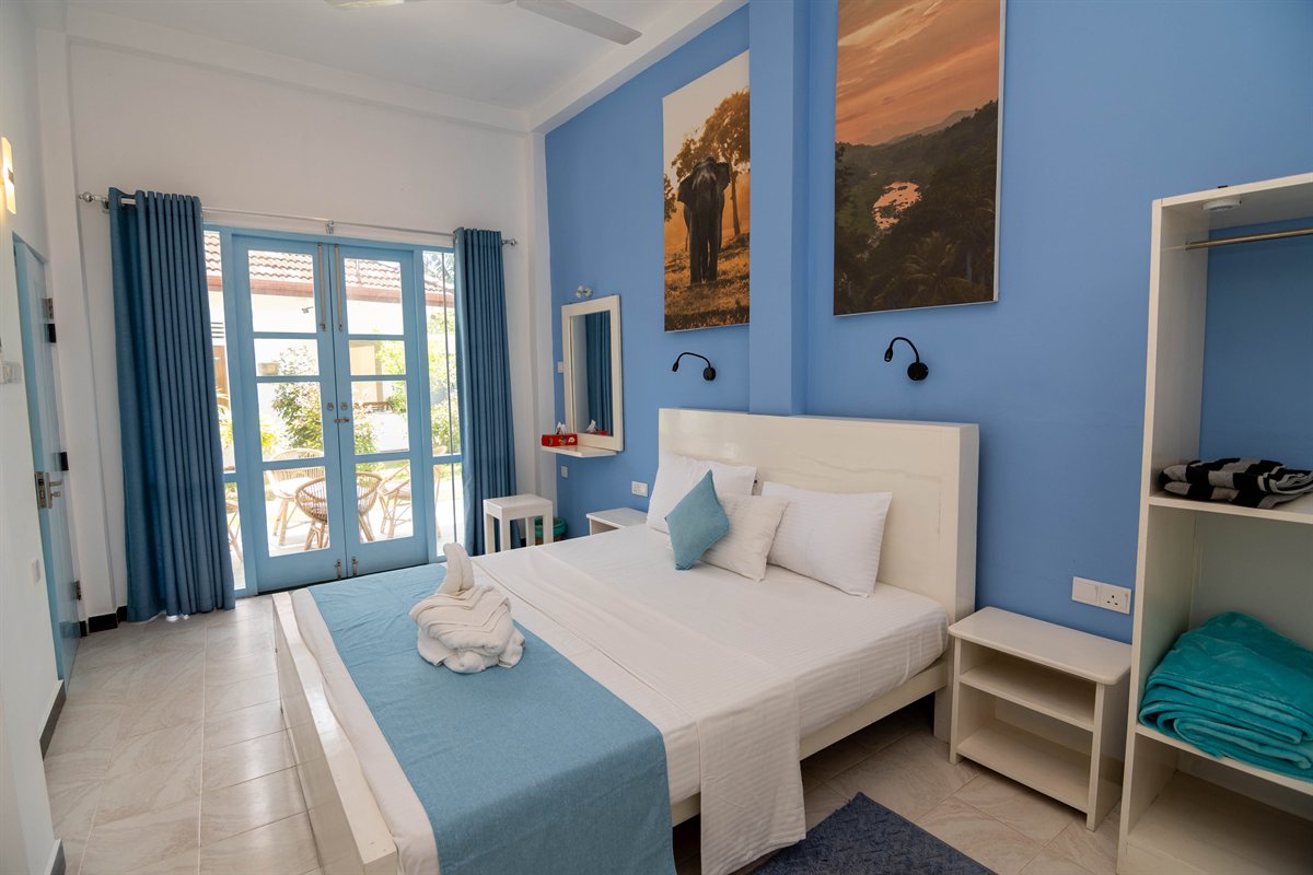 Blue-and-white bedroom with garden-facing doors at Tropical Garden Retreat