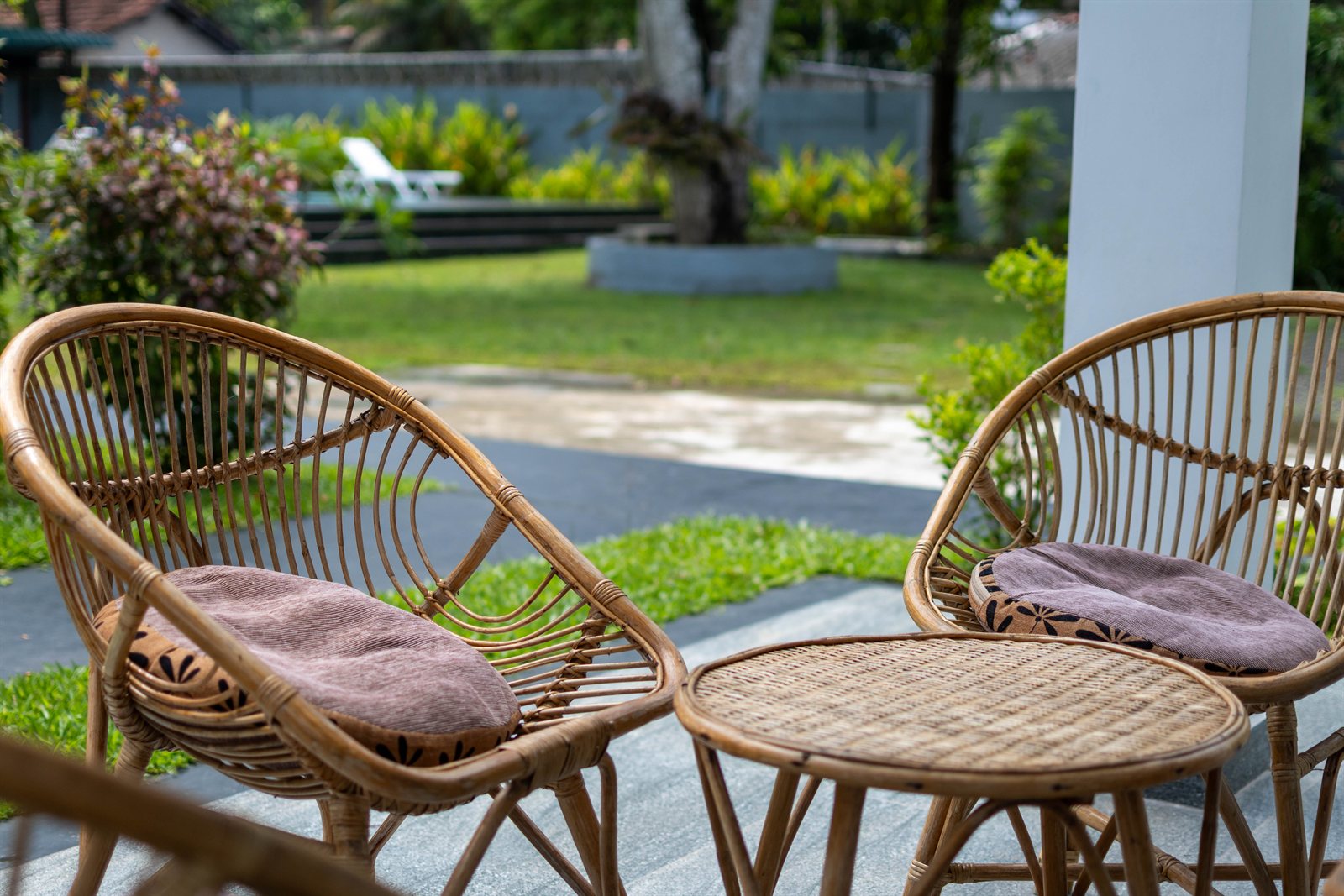 Rattan chairs on the ground-floor porch overlooking the garden at Tropical Garden Retreat