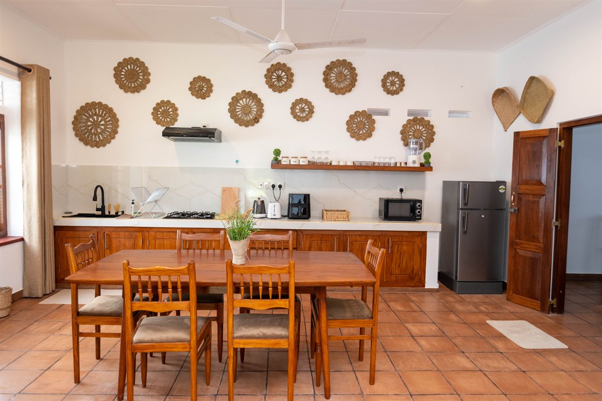 Private kitchen and wooden dining table with woven wall decorations at Heritage House Retreat