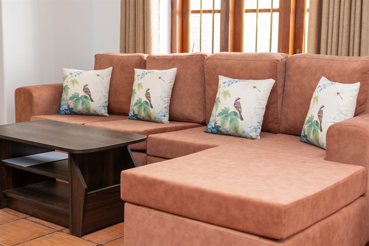 Terracotta-colored corner sofa with botanical cushions at Heritage House Retreat