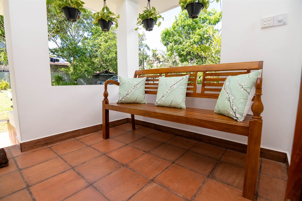 Wooden bench with cushions on the shaded porch at Heritage House Retreat