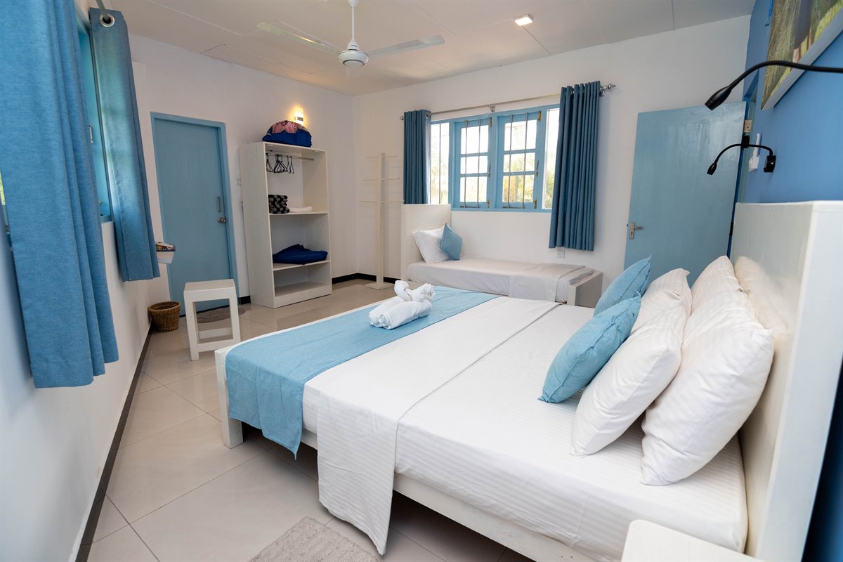 Blue-and-white bedroom with double and single beds at Tropical Palm View Retreat