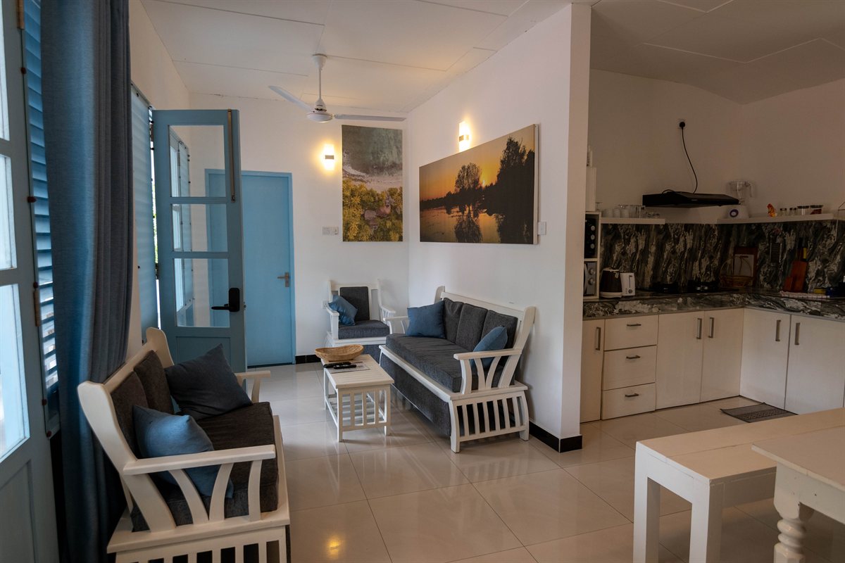 Blue-cushioned chairs and sofa in the bright living area at Tropical Palm View Retreat