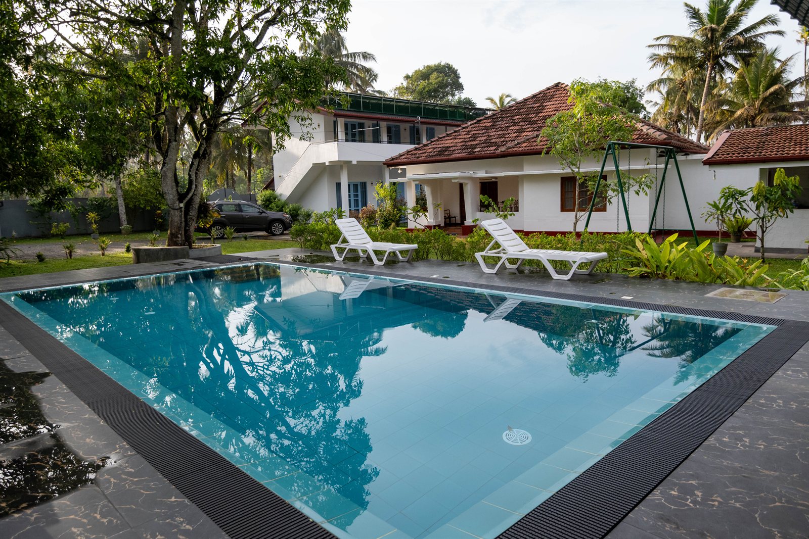 Shared swimming pool with sun loungers, palms and Heritage House in the background